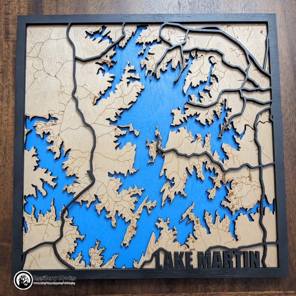 Map of Lake Martin made of laser-cut wood. Back layer is blue for the lake, middle layer is birch colored with minor roads engraved, top layer is black border with major highways and title "Lake Martin" in lower right corner.